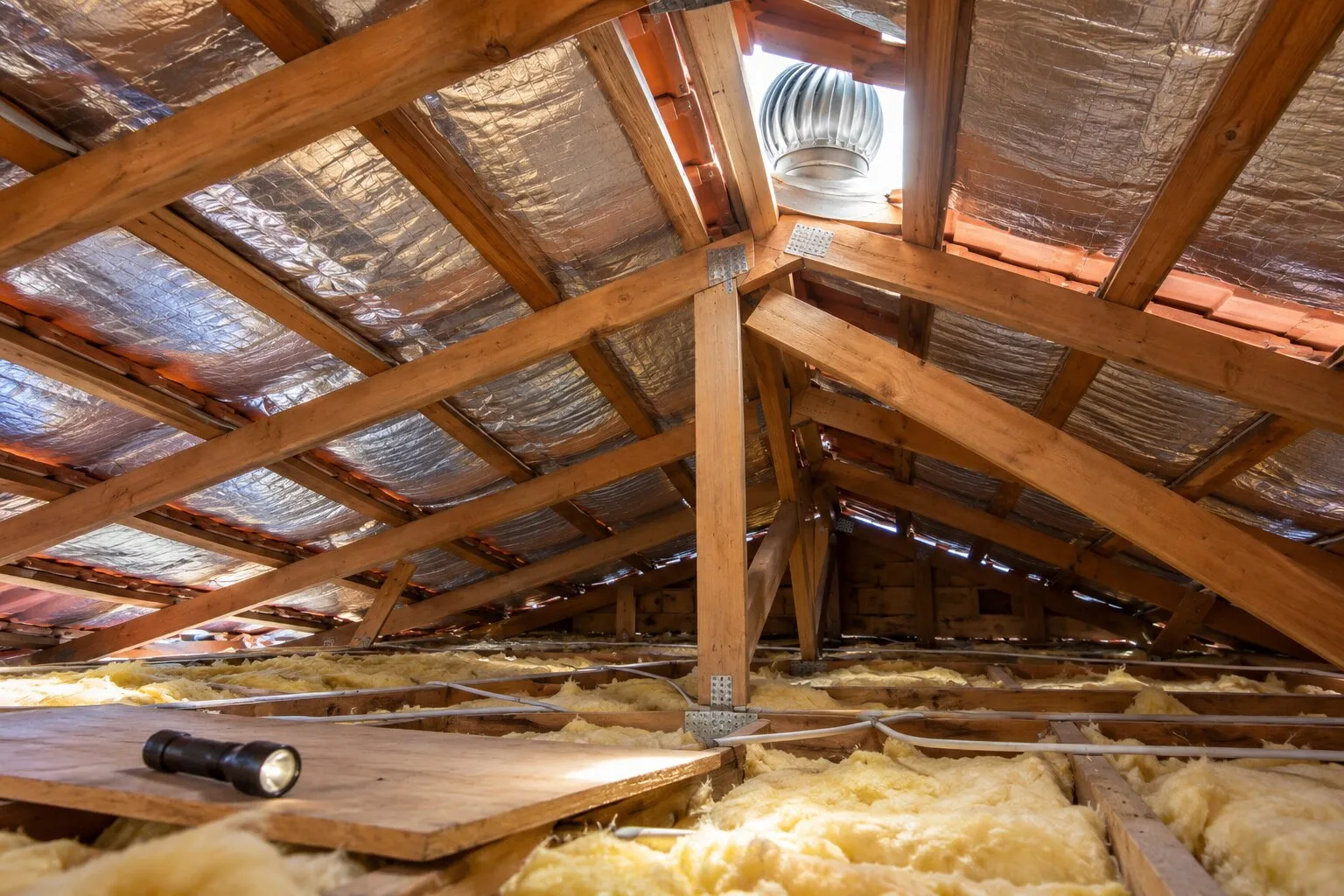 Roof sarking and whirlybirds, Northern Beaches: foil sarking under the battens of a tile roof space, a whirlybird vent near the ridge