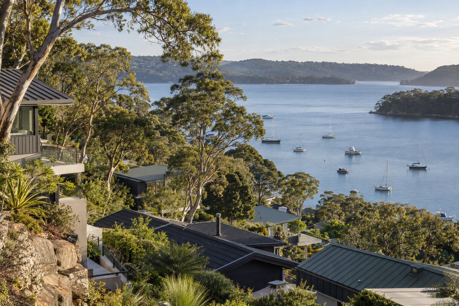 Roofing, Newport: steep hillside homes with dark roofs stepping down to Pittwater